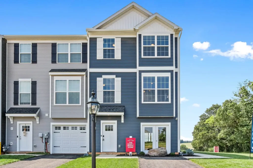 Three-story blue and gray Burkentine model townhome with attached garage and front lamp post