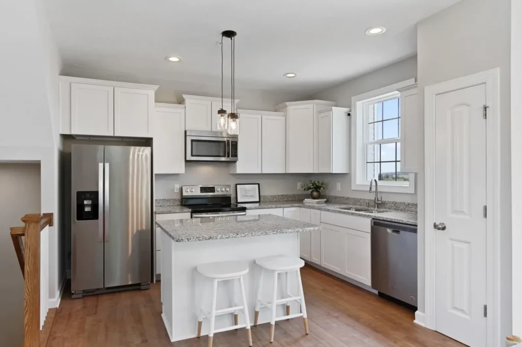 White Hudson kitchen with granite island, stainless steel appliances, pendant lights, and hardwood floor