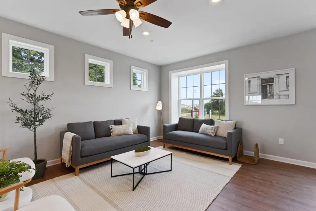 Hudson model living room with two gray sofas, central coffee table, large window, and neutral decor