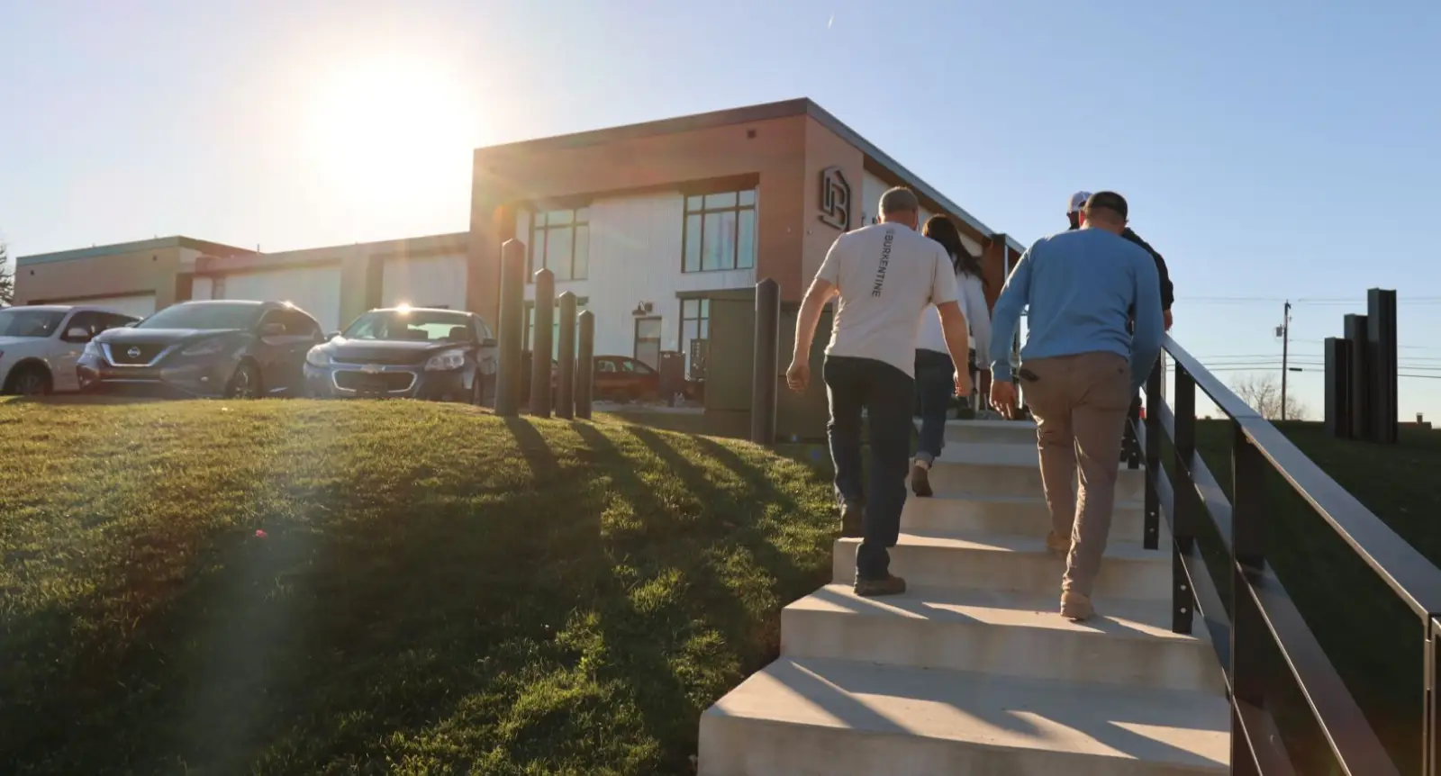 Burkentine team members walking up exterior stairs toward company office at sunset