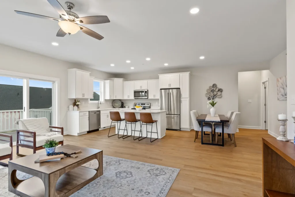 Open-concept kitchen and dining area with white cabinets, island seating, and hardwood floors