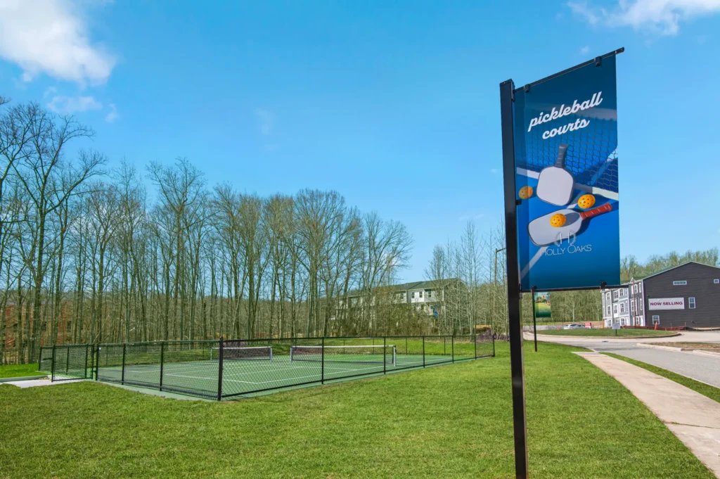 Outdoor pickleball courts and community banner at Holly Oaks with trees and nearby apartments