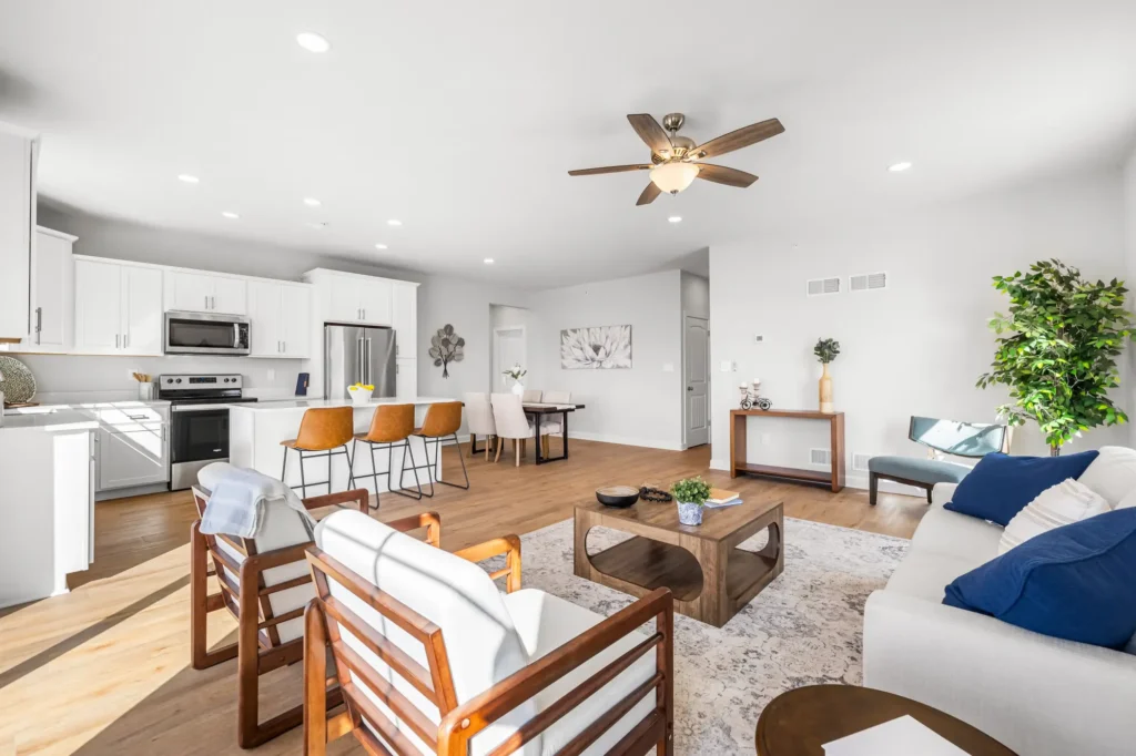 Open first-floor living area with kitchen island, three leather bar stools, dining table and hardwood floors
